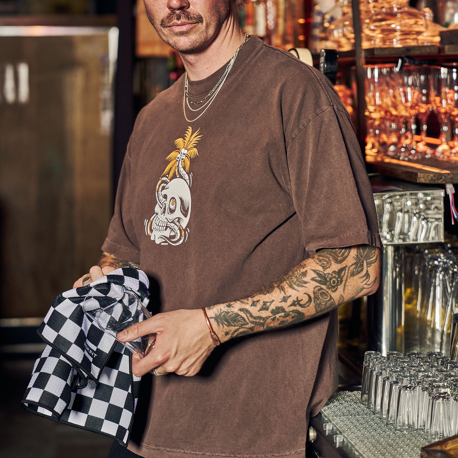 Male model using Utility Towel in bar cleaning a glass with 'Checker' graphic