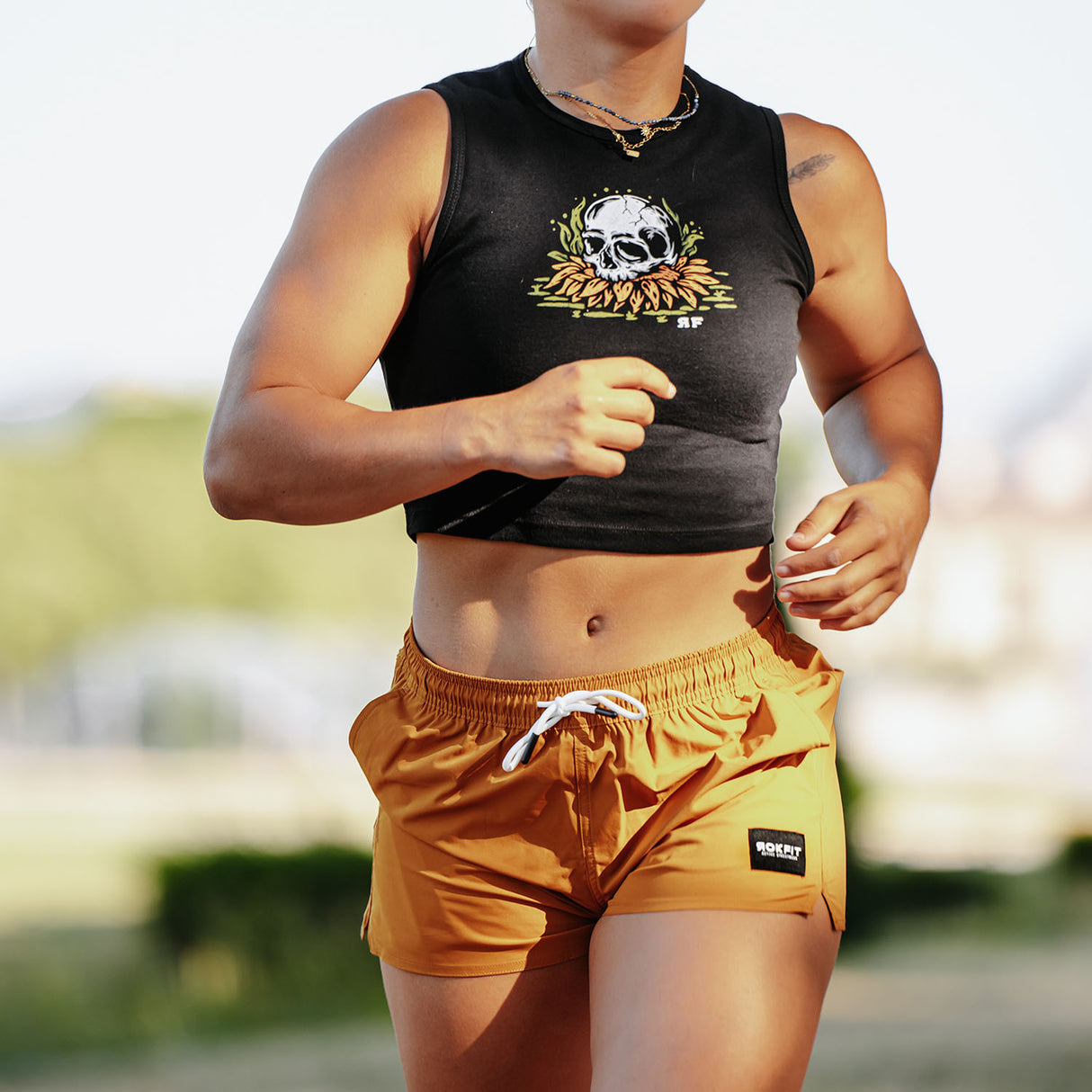 Female model running outdoors wearing women's gold Hybrid Shorts