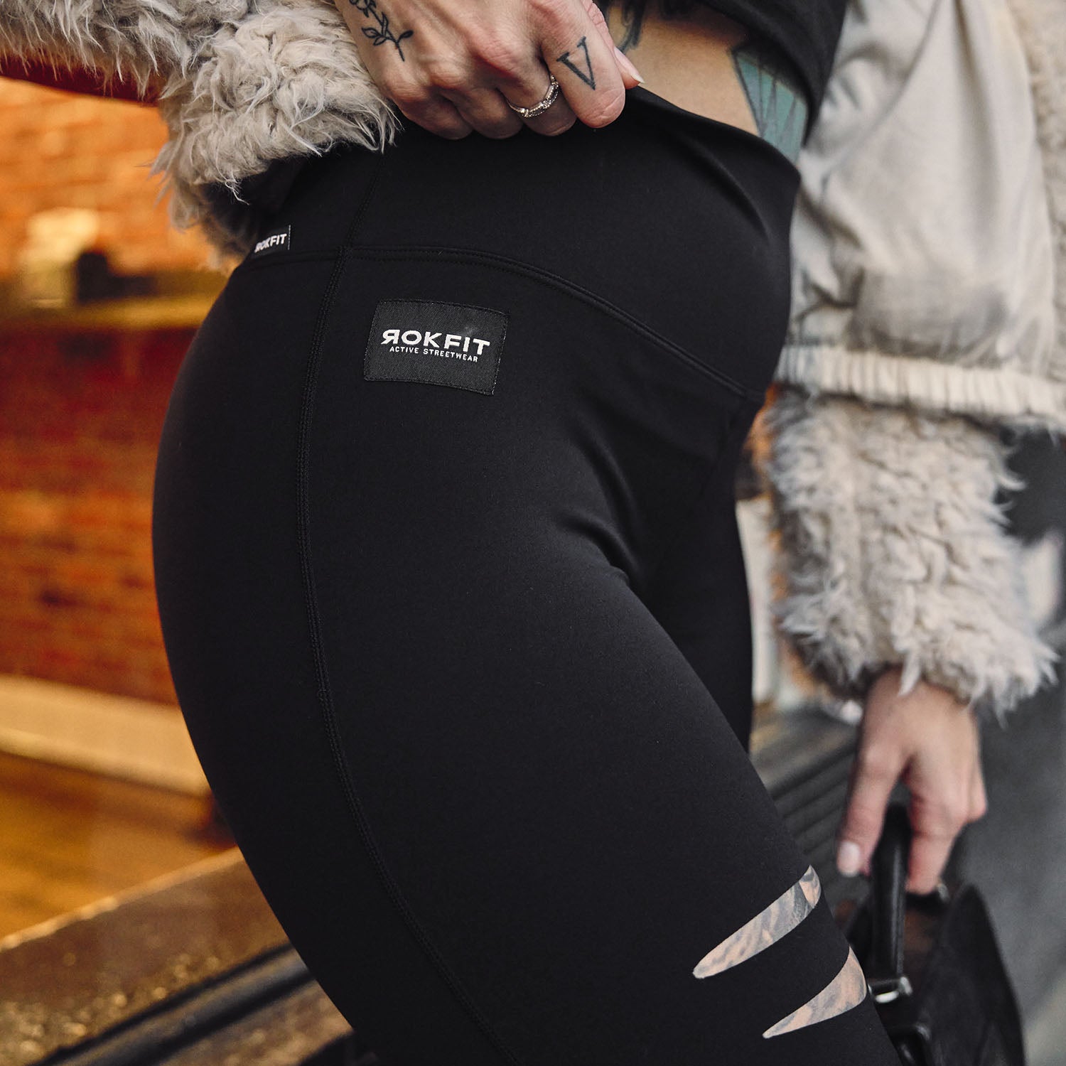 Female model outdoors wearing Cutline Leggings showing logo