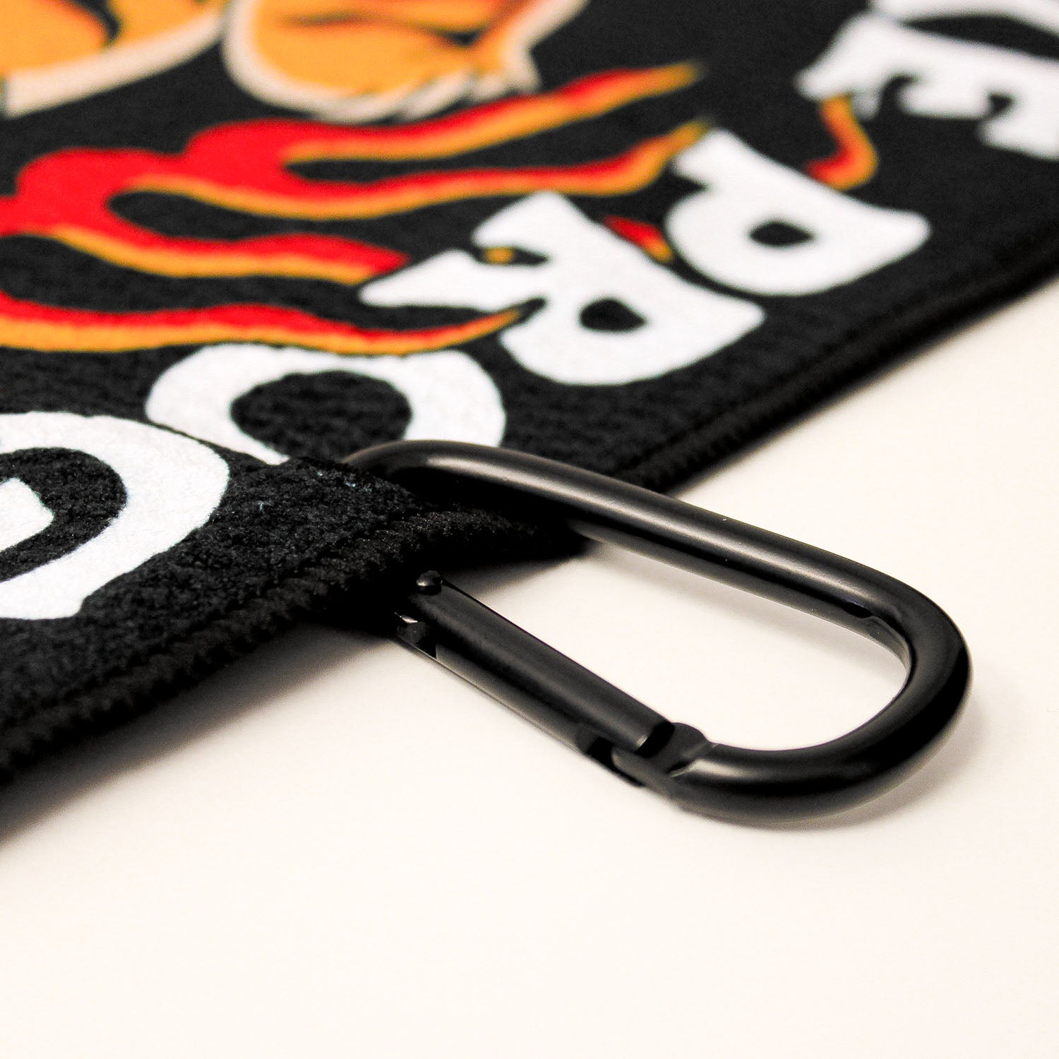 Close up of Utility Towel black carabiner clip with 'Make Excuses or Make Progress' graphic