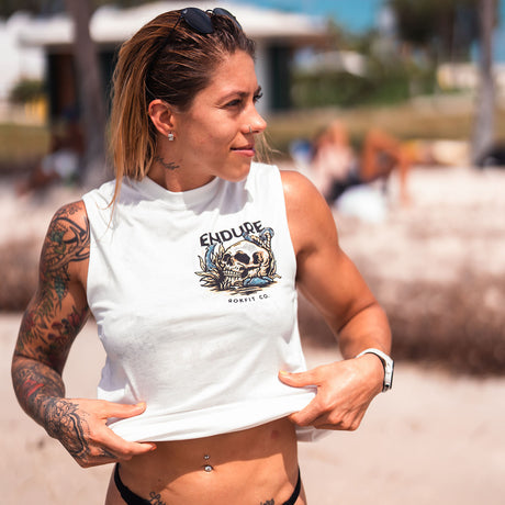 Female model outdoors wearing unisex sleeveless active tee with 'Endure' graphic