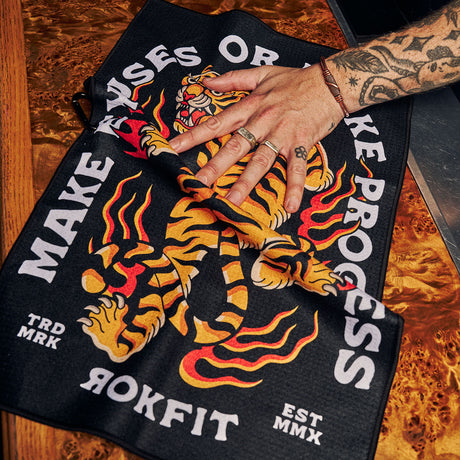 Male model using Utility Towel on bar top with 'Make Excuses or Make Progress' graphic
