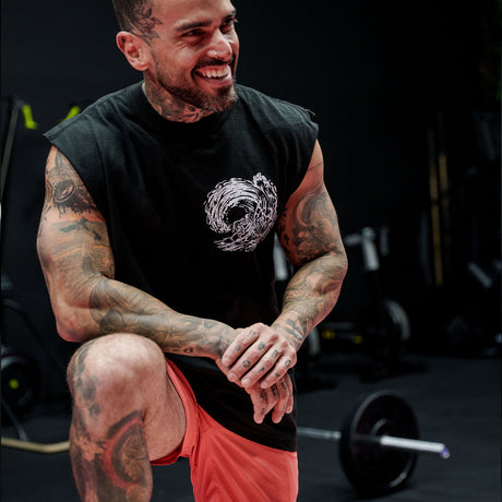 Male model in a gym wearing sleeveless Street Tee with 'Own The Grind' graphic