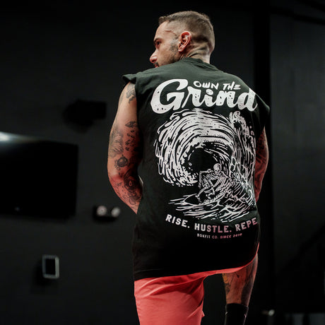 Male model in a gym wearing sleeveless Street Tee with 'Own The Grind' graphic