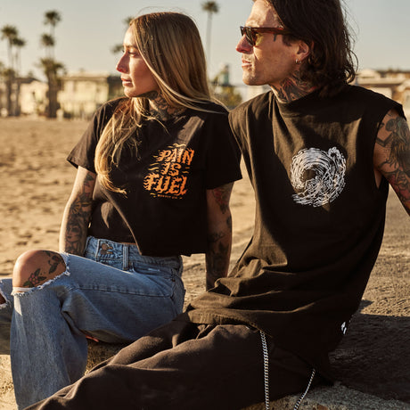 Male model outdoors wearing a sleeveless street tee with 'Own The Grind' graphic